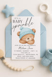 Baby sprinkle invitation with teddy bear graphic and baby items on a light background